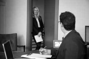 Black and white image of Janet Amburgey speaking to Patrick McCroskey from Patrick's office doorway.