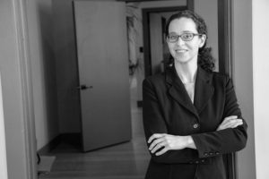 Black and white image of Elise Putnam standing in the doorway of her office in downtown Asheville with her arms crossed in front of her