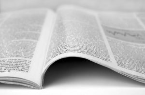 Monochromatic mage of a magazine opened nearly at the center with long format article covering both pages without images, fading away to the background.