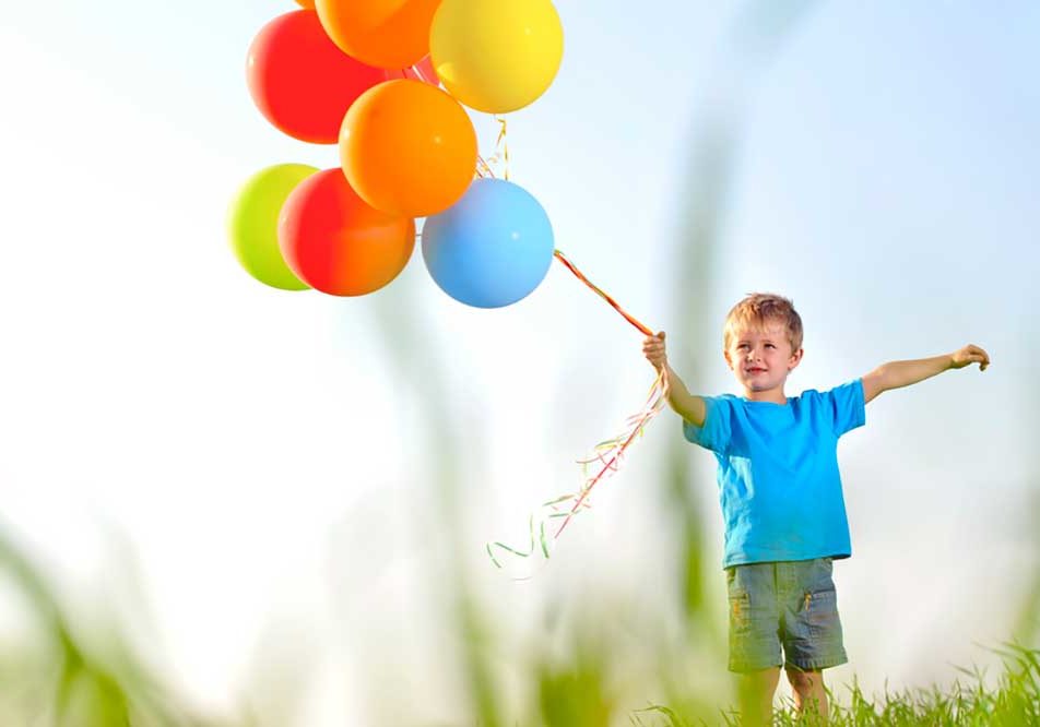 Divorce and Children Picture of a small boy in a field of grass holding a cluster of brightly colored helium balloons on a string