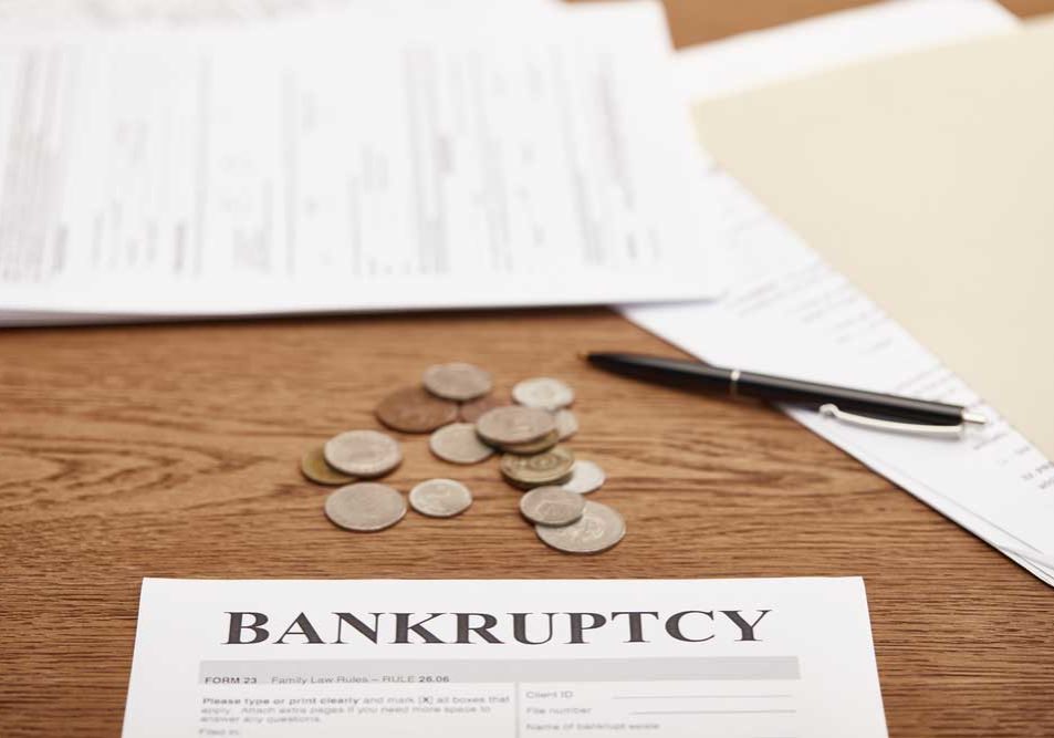 Bankruptcy Forms Image of forms and miscellaneous paperwork on a wood desk.