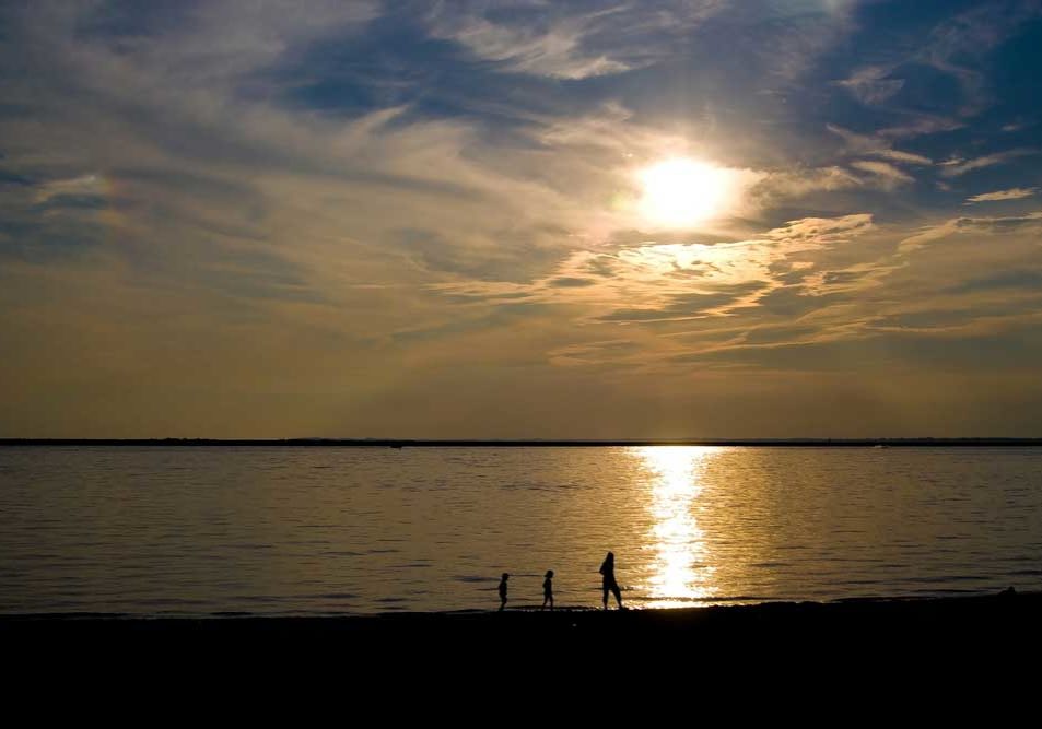 Family in Silhouette at Dusk Single parent and two small children walking on the distant beach at dusk in silhouette.
