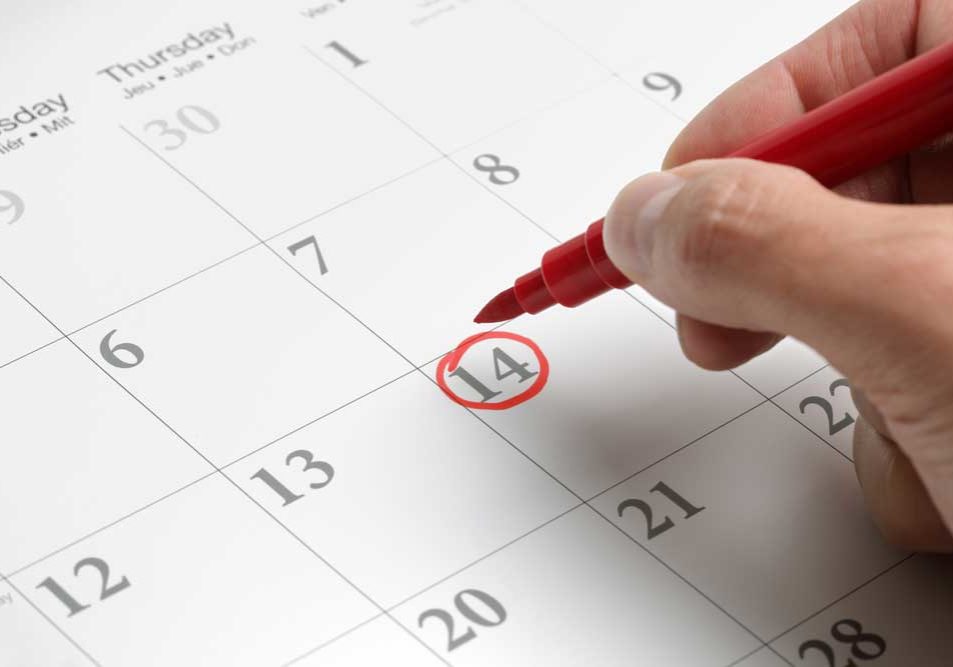 Calendaring Events Image of a desk-sized calendar in monthly grid view with a person's hand circling a date with red magic marker.