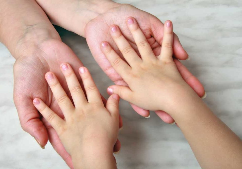 Child Support Image of small child with hands, palms face down, in the hands of an adult, depicting child support