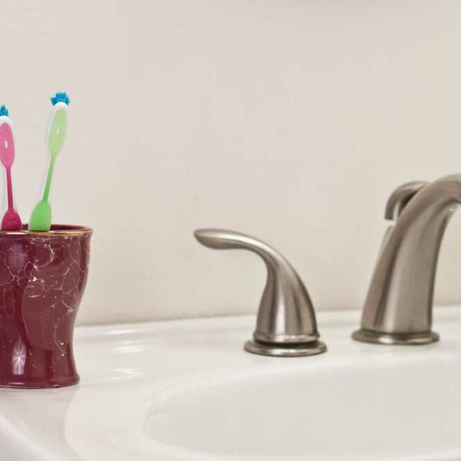 Image of two toothbrushes on a bathroom sink depicting living together