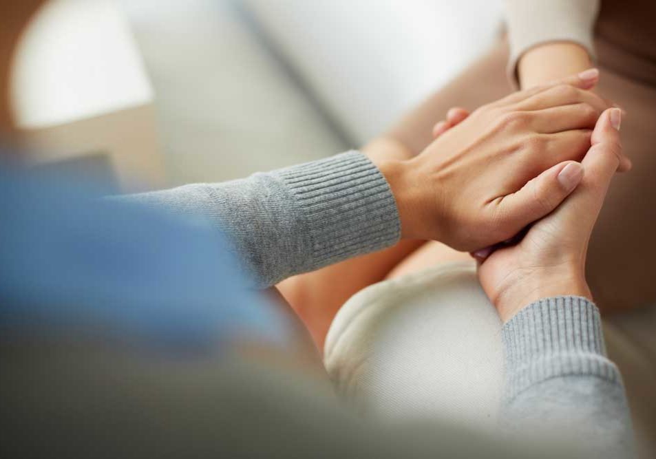 Get Counseling Image of a counselor comforting a patient by holding her hand depicting successful use of therapy through divorce.