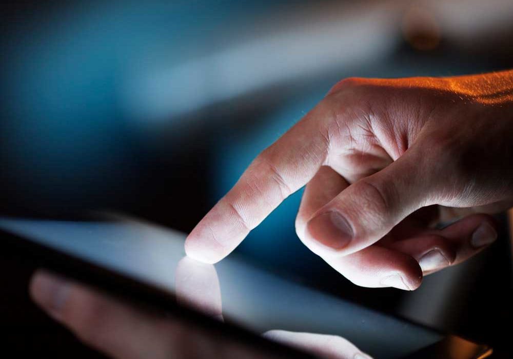 Tablet Man's hands holding and using a backlit digital tablet in low light ambience room