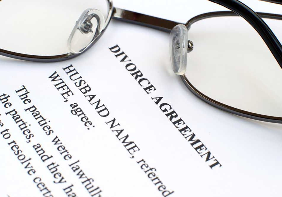 Divorce Agreement Image of a typewritten agreement for divorce on white paper with a pair of eyeglasses folded on top of it.