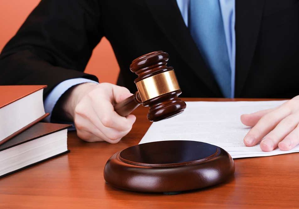 Gavel Image of a man in a black suit and blue tie, cropped without a face, pounding a gavel.
