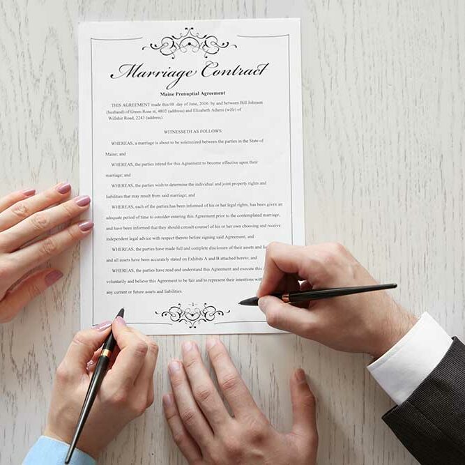 Stock photography image of a Marriage Contract on a table with the hands of a man and a woman signing it.