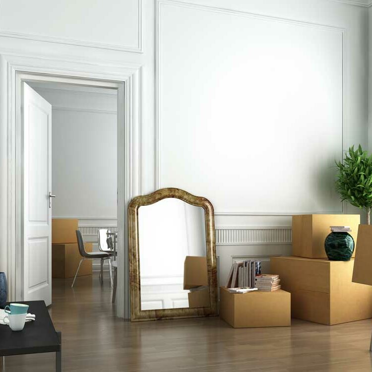 Image of empty room with high ceilings and shiny wood floors with seeral boxes packed and ready to go depicting relocating.