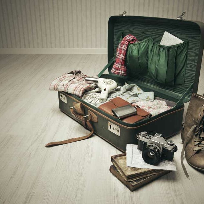 A vintage suitcase half neatly packed with necessities and important items in preparation for leaving.