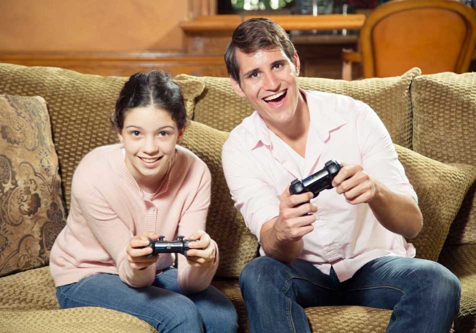 Siblings Siblings of significantly different ages playing video games together and smiling
