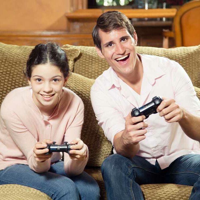 Siblings of significantly different ages playing video games together and smiling