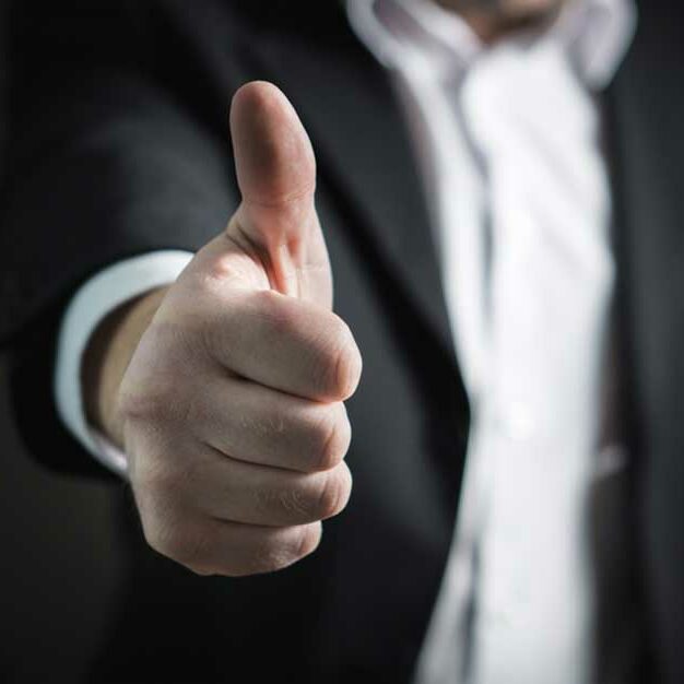 Stock Photography image of man in gray suit doing the thumbs up gesture.