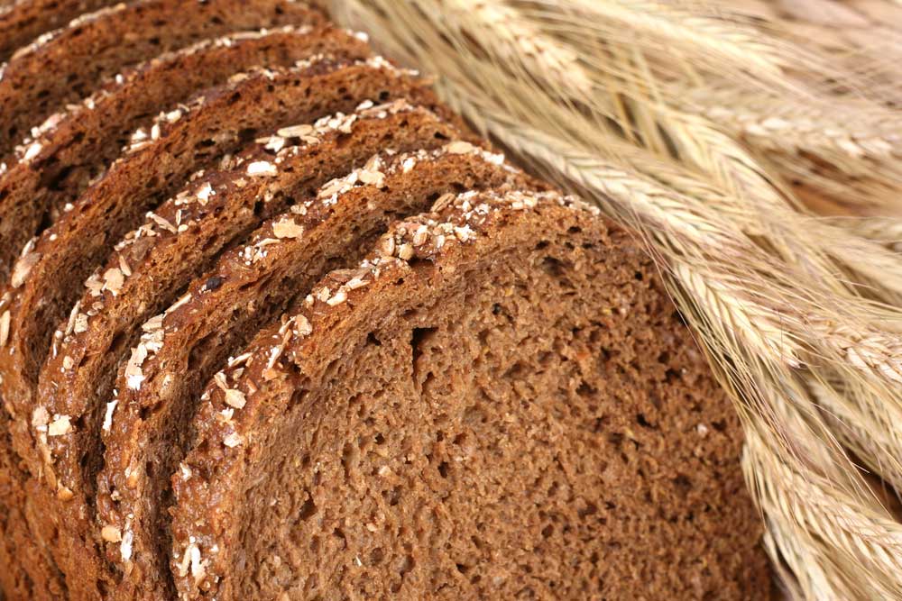 Image of sliced brown bread with stalks of wheat referencing the idea of a "breadwinner".