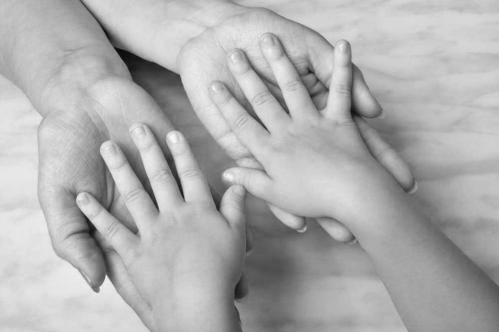 Image of small child with hands, palms face down, in the hands of an adult, depicting child support