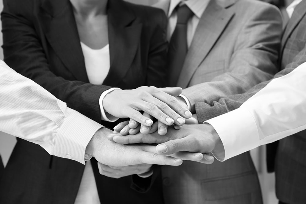 Image of a group of professionals with their hands stacked in representation of teamwork.