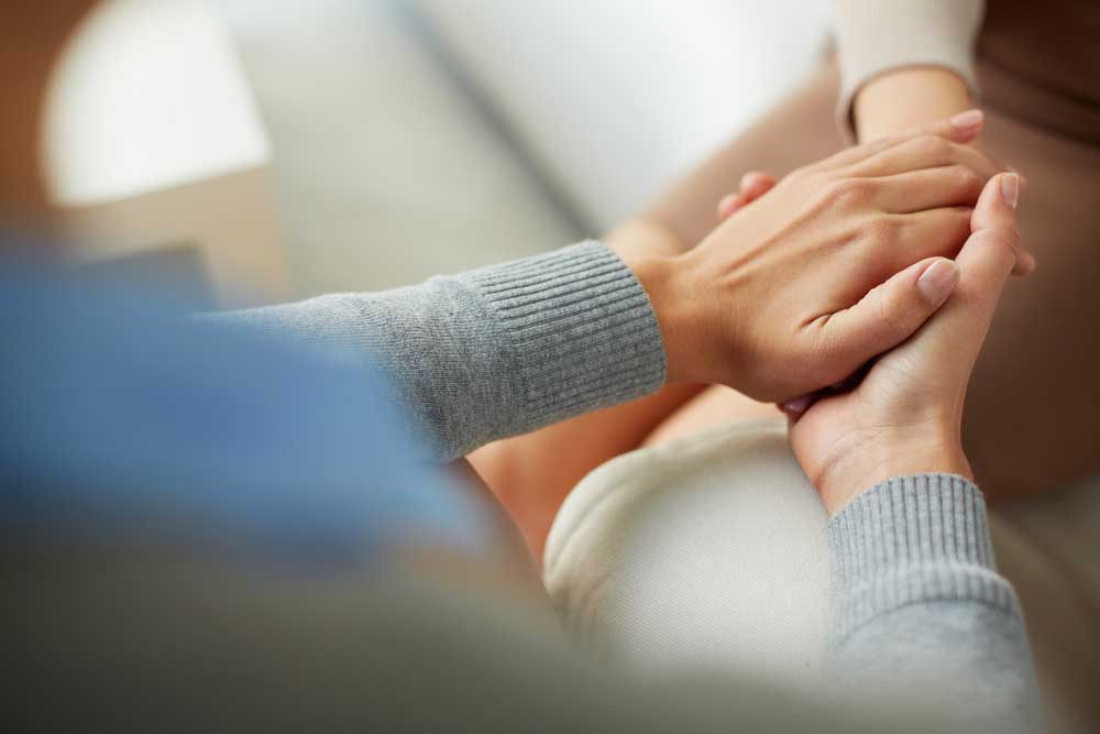 Image of a counselor comforting a patient by holding her hand depicting successful use of therapy through divorce.