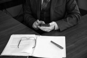 Custom stock image of Patrick McCroskey at his desk sending a text message, while working on a client's custody file.