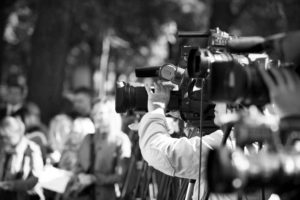 Image of a throng of news media with cameras pointing toward and recording an unknown newsworthy event.
