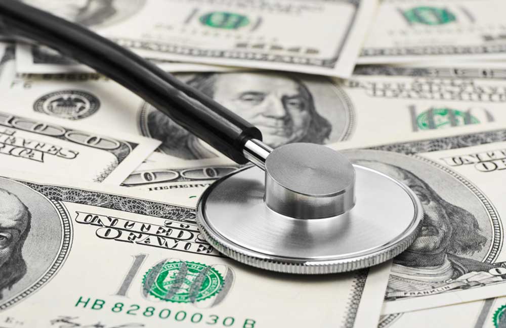 A pile of money with a stethoscope depicting monitoring of financial health.