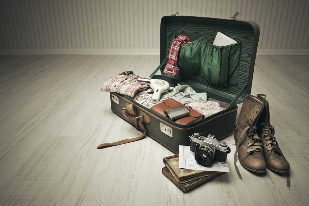 A vintage suitcase half neatly packed with necessities and important items in preparation for leaving.