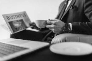 Black and white stock photograph of a businessman holding a cup of coffee and a newspaper denoting Patrick's News on the firm's blog.