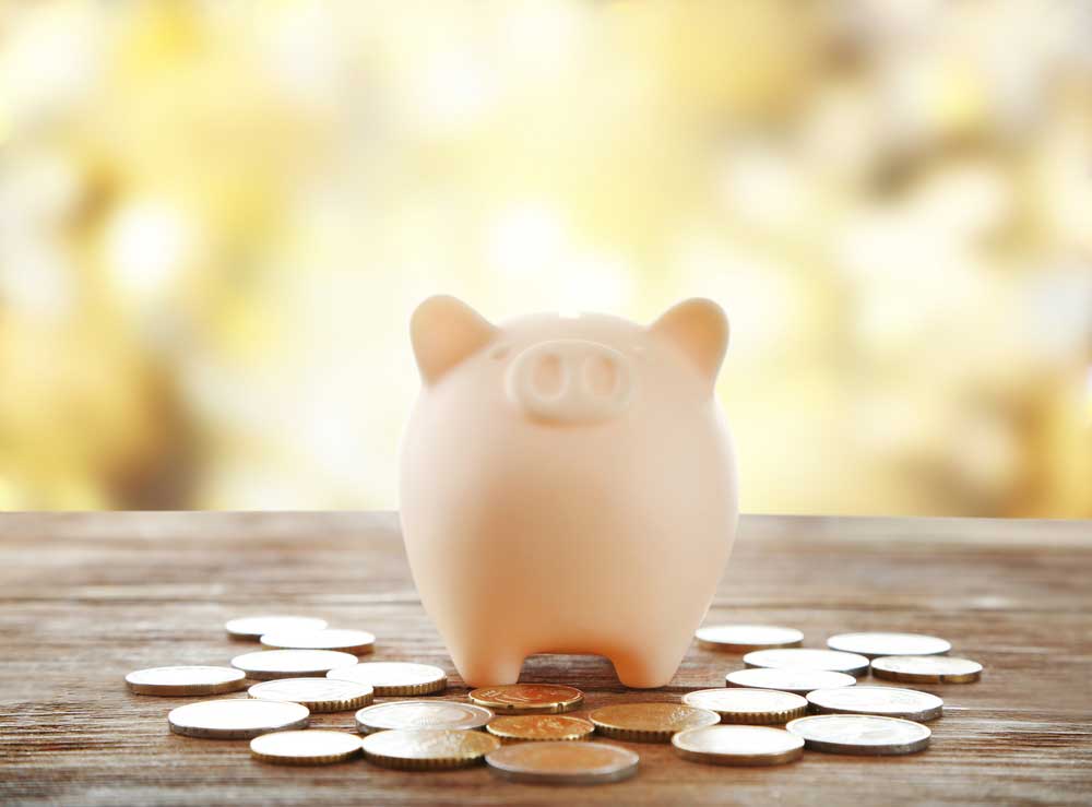 Image of a ceramic pig bank with change spread across a wooden table denoting costs of a divorce.