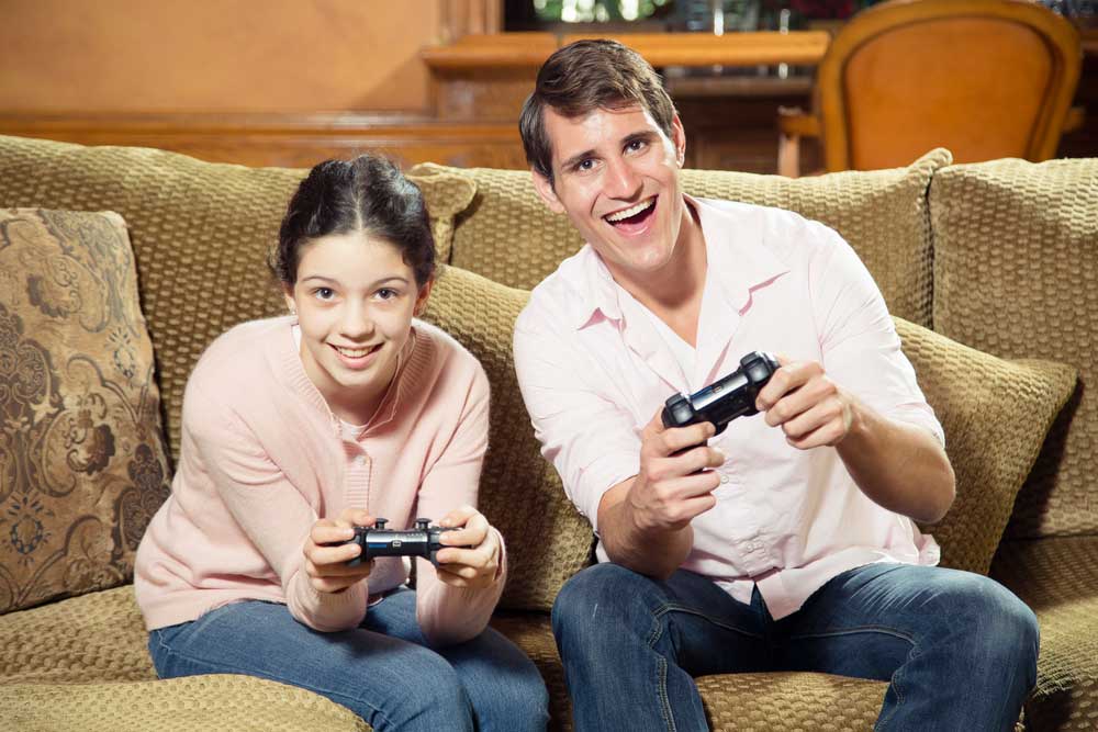 Siblings of significantly different ages playing video games together and smiling