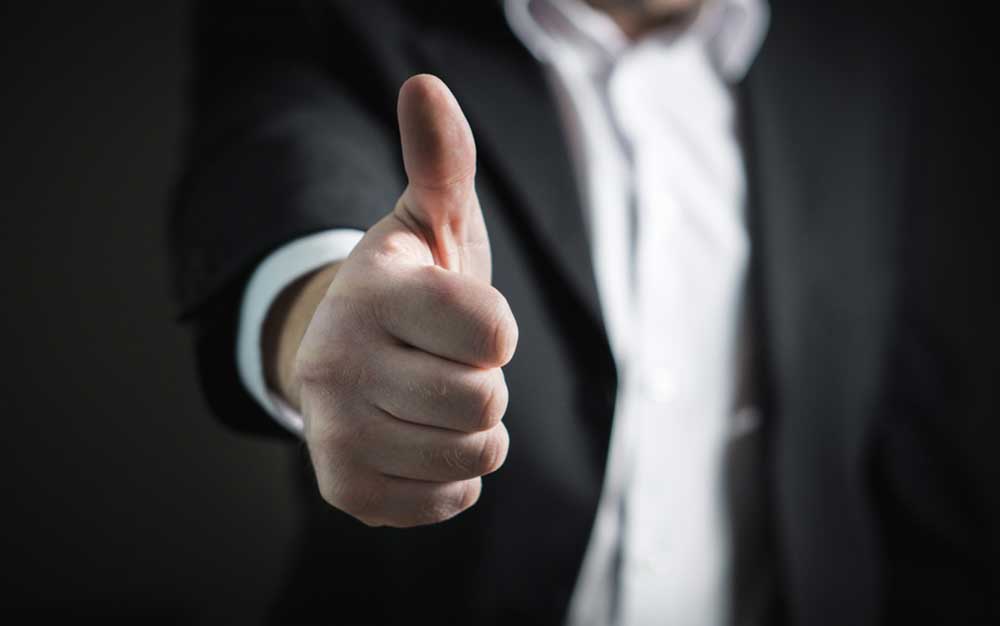 Stock Photography image of man in gray suit doing the thumbs up gesture.